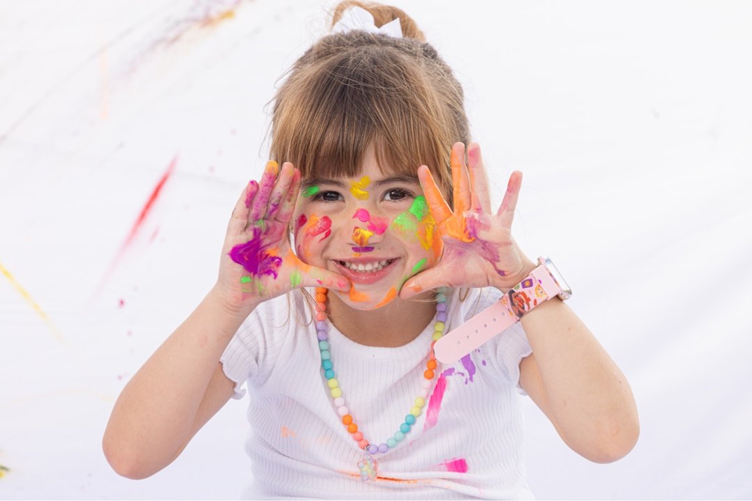 Manos de niña llenas de pintura de colores